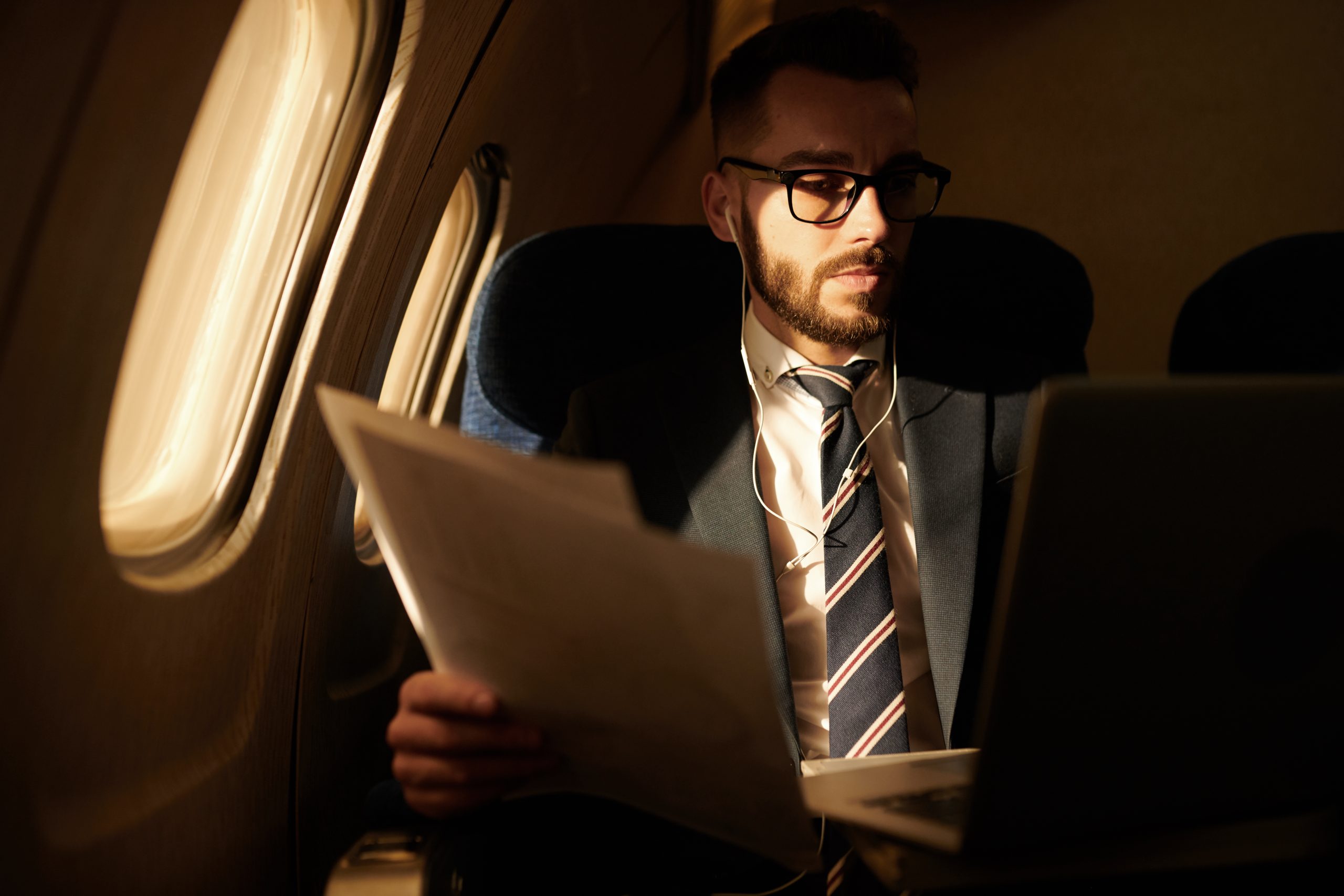 Portrait of successful young businessman working in dim plane while enjoying first class flight, copy space